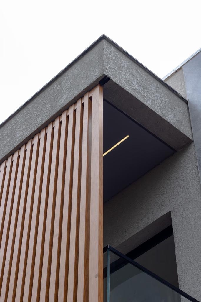 Detalhe de fachada com painel ripado em madeira e concreto aparente